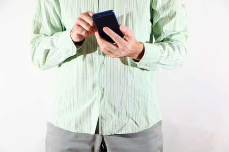 A businessman in a light green shirt and light trousers, a smartphone in his hand. A male model in a...