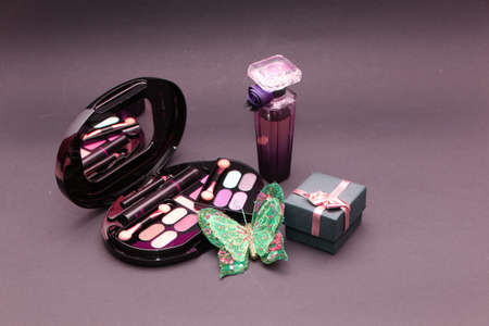 Perfume set on a wooden table is decorated with a bouquet of carnations. The background is black. Beautiful perfume bottle and female makeup on the background of a bouquet of carnations.の写真素材