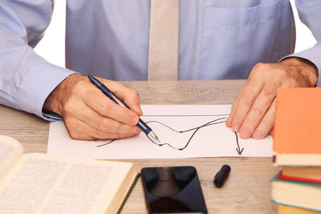 A businessman in a blue shirt and beige tie in the office holds a smartphone in his hand, a globe,...