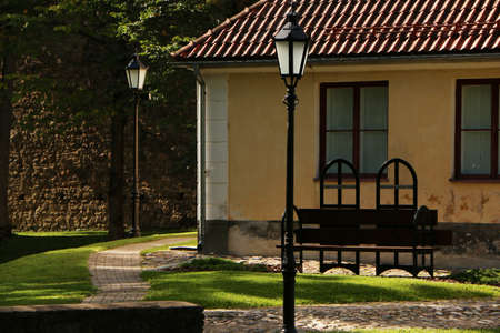 Ancient wooden bench. An old bench against the background of an old lantern and the wall of the house.の写真素材