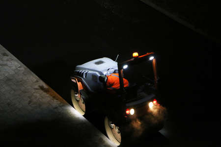 Road repair works at night. Modern machines for the repair and paving of new asphalt.