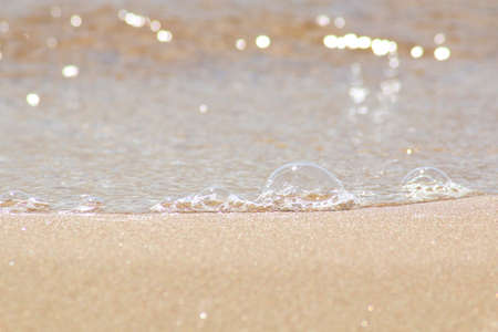 Against the background of sea sand bubbles from the sea wave. Beautiful background - sea wave on the sandy shore.の写真素材