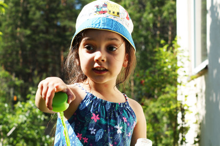 The girl blows bubbles in the summer in nature. Close up of a child blowing bubbles.の写真素材