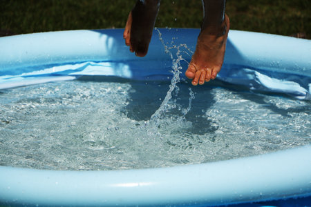 A child is swimming in an inflatable pool. A girl is jumping into the water in an inflatable pool.の写真素材