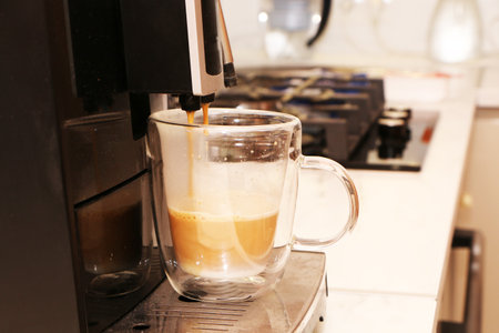 A man prepares aromatic delicious coffee in an automatic coffee machine. Coffee with milk is prepared in a coffee machine.の写真素材