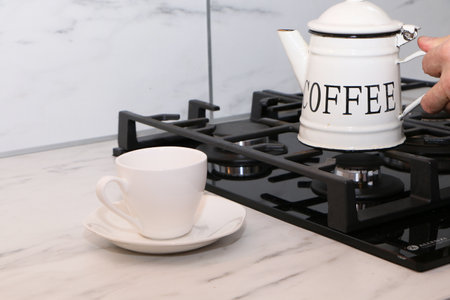 Coffee pot and cup on the gas stove in the kitchenの写真素材