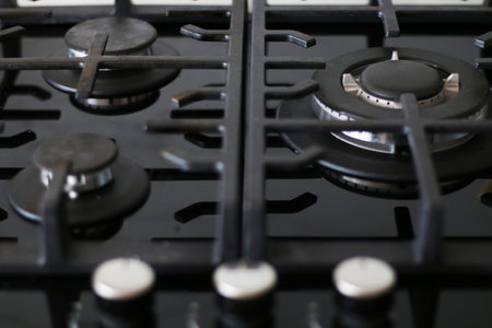 Black ceramic gas stove close-up. Blue flame on a working modern gas stove.の写真素材