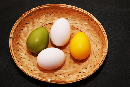 Painted eggs in a wicker basket for Easter. Colored eggs close-up on a black background.の写真素材