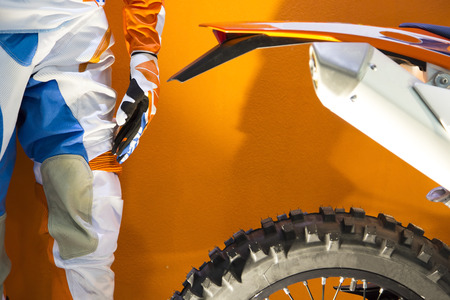 Closeup image of a motocross biker protective clothing and motocross bike on orange backgroundの写真素材