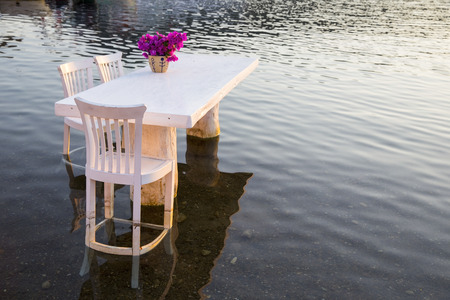White wooden table and chairs in the sea waterの写真素材