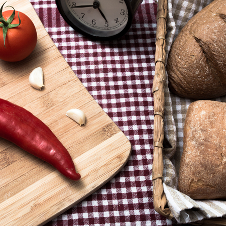 Home bread and bread basket with pepper tomato on table clothの写真素材