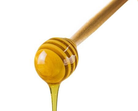 Close up of honey dripping from wooden drizzler drop, isolated on white background.の写真素材