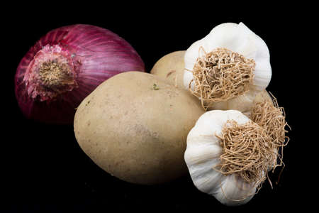 Potatoes, garlics and onion on isolated black background.の写真素材