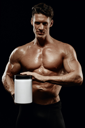 beautiful young athletic man holding a jar of sports nutritionの写真素材