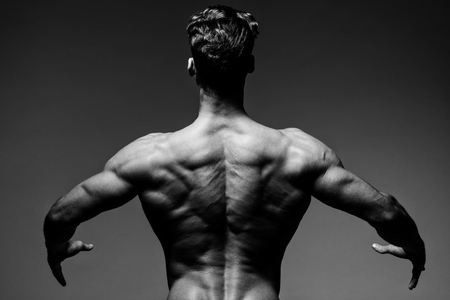 Rear view of healthy muscular young man with his arms stretched outの写真素材