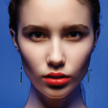 portrait of a beautiful young brunette woman in the studio on a blue background, the concept of beautyの写真素材
