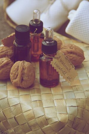 Bottle of walnut essential oil on the woven surface. Walnuts in the backgroundの写真素材
