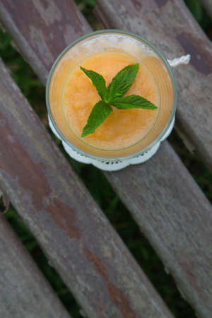 A glass of smoothie melon-kiwi on the old wooden surface. Top view