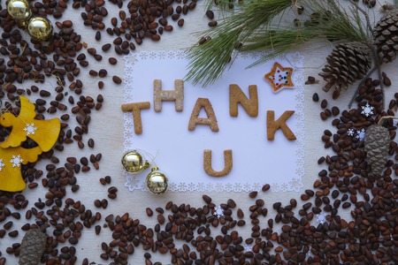 Winter holidays cedar nuts background on a wooden surface with  biscuits inscription:"Thank u"の写真素材