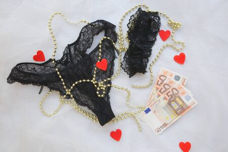 Love and sex for money: lingerie,hearts, golden like perls, garter band and euro on a transparent fabric.の写真素材