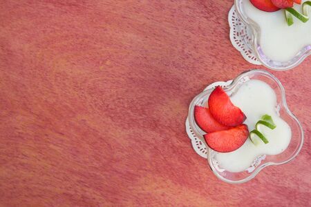 Milk dessert - sweet ricotta cheese with plums - in a glass dessert bowl. Top view. Free space for a text.の写真素材