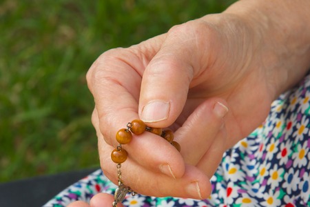 Christian prayer beads in the hand of old womanの写真素材