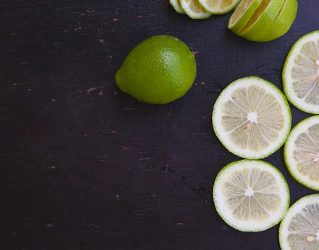Green lemon slices on a black wooden surface. Background. Free space for a textの写真素材