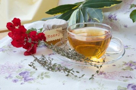 A glass cup of thyme herbal tea with honey on a table cloth.の写真素材
