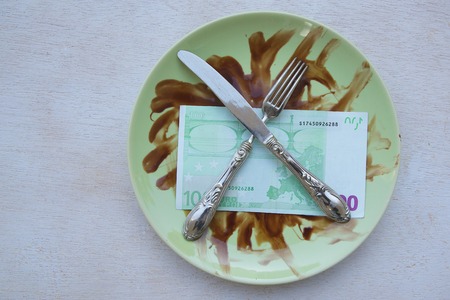 Money, fork,knife are placed on a dirty green plate. Free space for a textの写真素材
