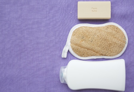 Personal hygiene items on a violet fabric: shower gel,bath sponge,a bar of soap. Backgroundの写真素材