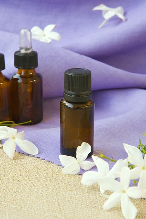 A dropper bottle of jasmine essential oil. Jasmine blossoms in the backgroundの写真素材
