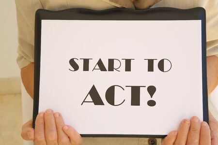 Message on a white surface in the hands of senior woman: "Start to act"の写真素材