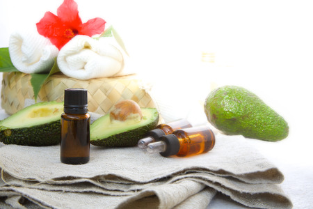 A dropper bottle of avocado oil on a grey sackcloth. Fresh avocado in the background. Free space for a textの写真素材