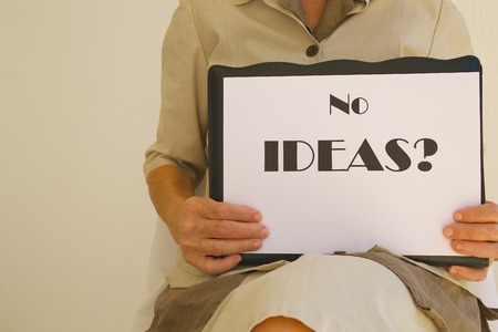 Message on a white surface in the hands of senior woman: "No ideas?"の写真素材