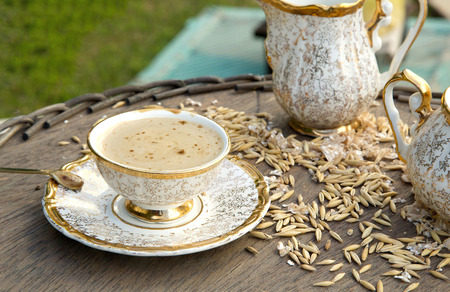 Healthy breakfast drink in an old porcelain cup: coffee substitute barley drink.Barley grains and flakes in the background.の写真素材