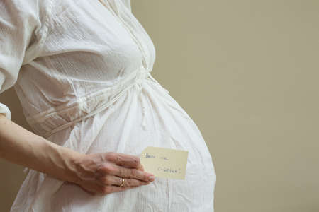 Birth via c-section. The pregnant woman keeps a piece of paperの写真素材