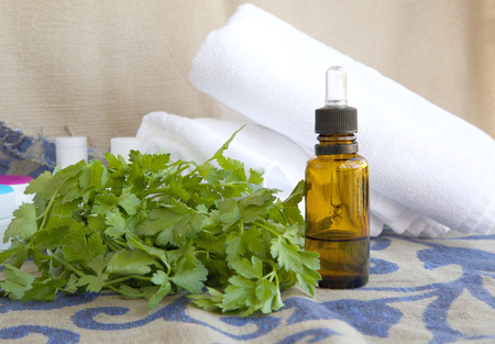 A dropper bottle of parsley essential oil. White towels in the backgroundの写真素材