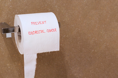The words prevent colorectal cancer is written on a roll of white patterned toilet paper hanging on a holder in a bathroom.Free space for a text.の写真素材