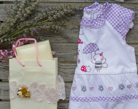 A present for a newborn girl: jewellery in a box, a violet dress on a gray wooden surface. Overhead perspective.の写真素材