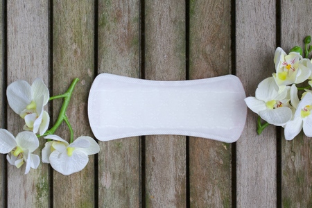 Everyday female pantyliners with artificial orchids heads  on a wooden surface covered by moss. Background.の写真素材