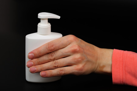 Dispenser with disinfectant and a mask on a black background.Closeup