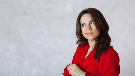 A young woman between 30 and 40 years old dressed in a classical red jacket reflects on somethingの写真素材