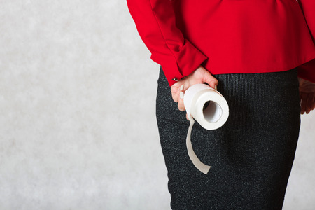 A young woman keeps a roll of a toilet paper close to her buttocksの写真素材