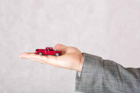 A small red toy car in the hand of a business man. Closeup. Free space for a text.の写真素材