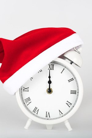 White vintage alarm clock on a gray background in a Santa Claus hat.の写真素材