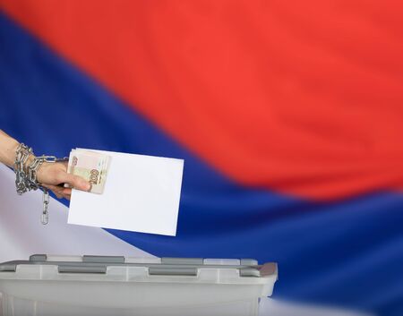 Female hand casts ballot paper in the ballot box. Russian flag in the background.の写真素材