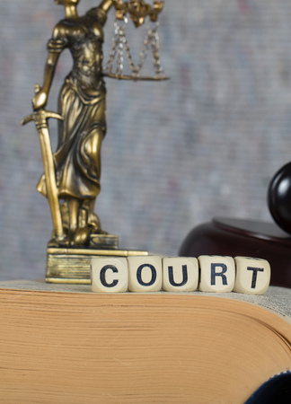 Word COURT composed of wooden letters. Statue Themis and judge's gavel in the background.の写真素材