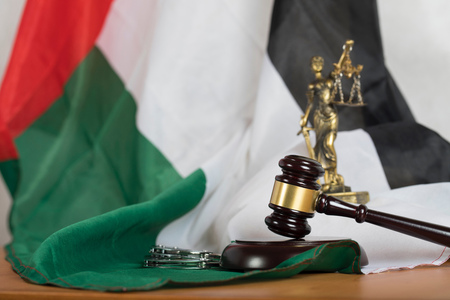 Judge's gavel on a flag of the United Arab Emirates. Statue of Themis and handcuffs in the backgroundの写真素材