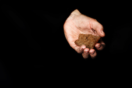Palm of a peasant woman with rye bread on a black fabric. Closeup  Palm of a peasant woman with oat grains on a black fabric. Closeupの写真素材