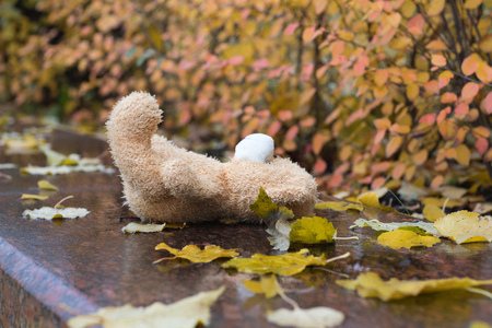 Brown plush teddy bear lost on a wet marble stone.の写真素材